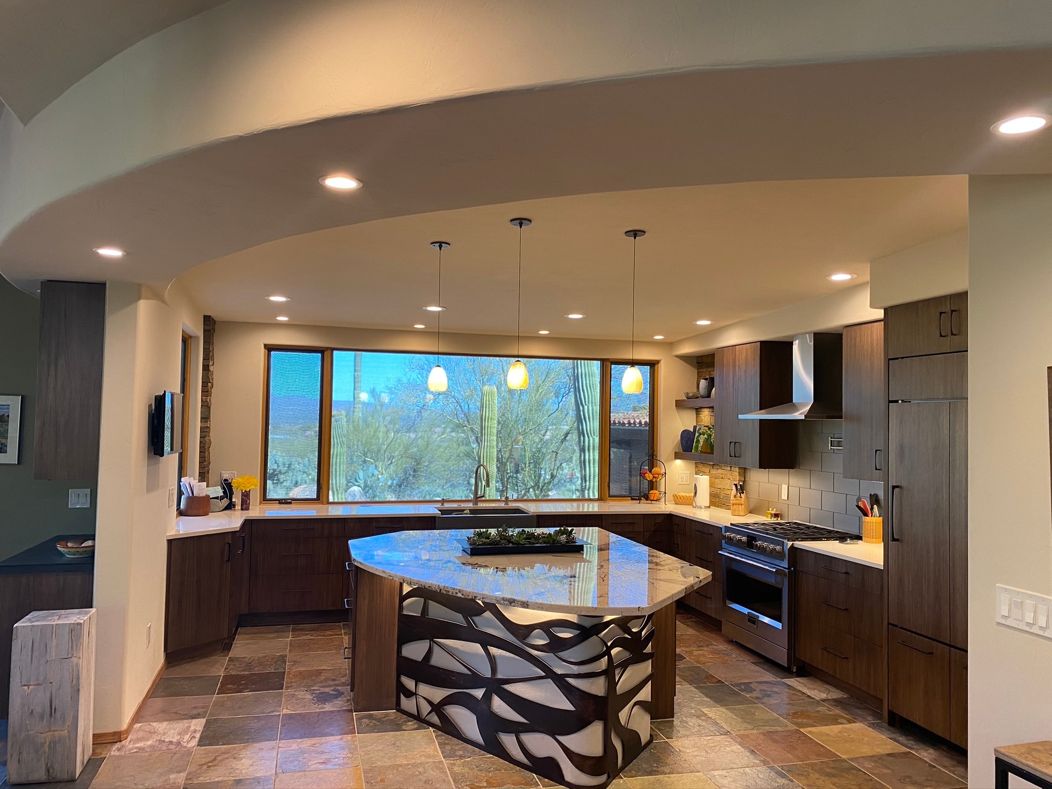 Modern kitchen remodel with curved granite island, dark cabinetry, and desert view — Birchard Remodeling Tucson