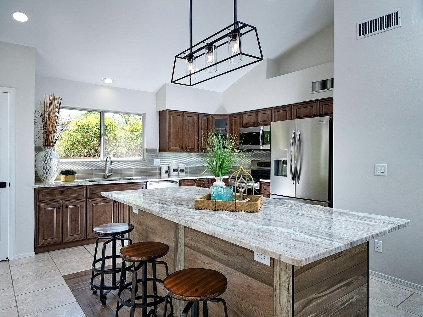 Bright kitchen remodel with marble island, walnut cabinetry, and industrial pendant lighting — Birchard Remodeling Tucson